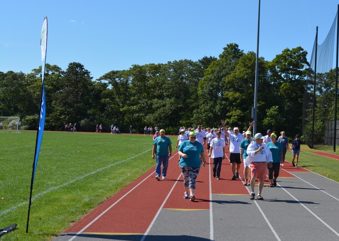 People walking on a track with a finish banner in the foreground