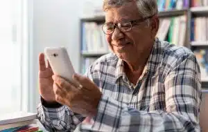 Happy elderly Asian using smartphone at home.