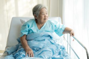 Elderly patient alone in bed. Alone and stress, missing her grand children. Looking at window. Very senior, old chinese woman.