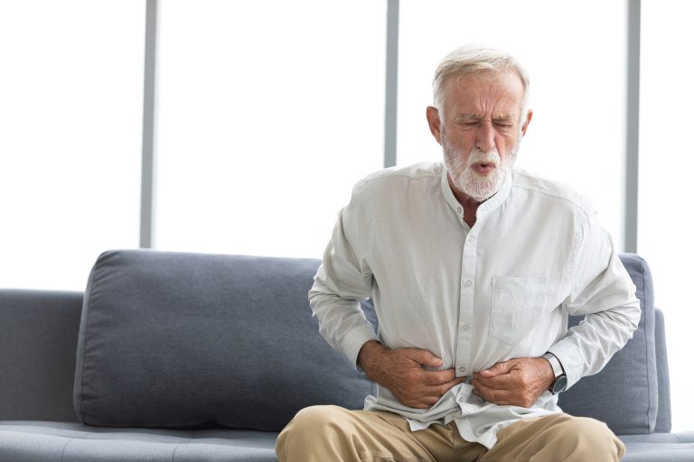 senior man have a stomachache and holding stomach on sofa