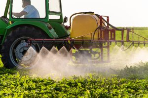 Tractor spraying pesticides on soy field with sprayer