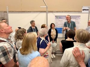 Dr. Rebecca Gilbert greets Dr. Bas Bloem at our poster about bridge funding as he leads a poster tour at WPC.