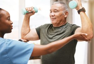 man lifting weights with a physical therapist