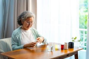 Asian elderly woman taking medicine at home.