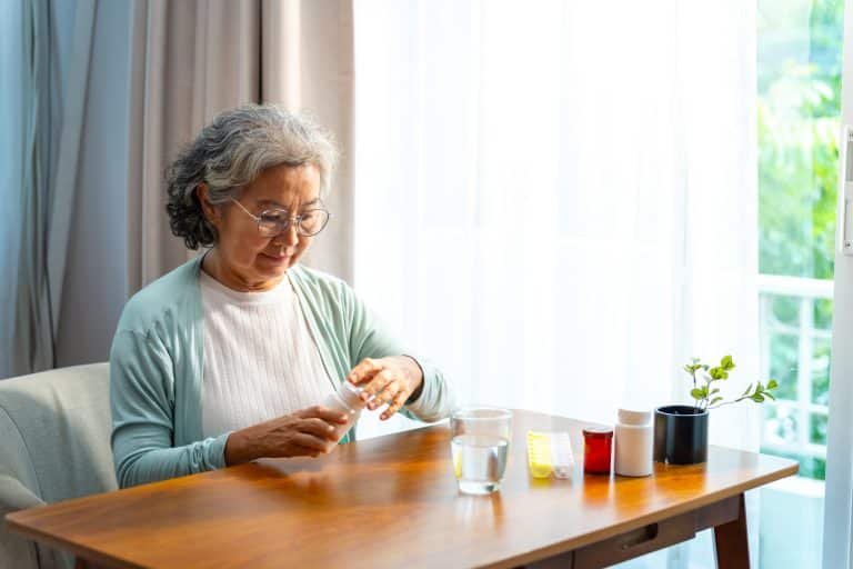 Asian elderly woman taking medicine at home.